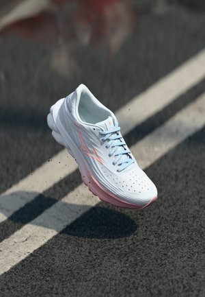 Baskets de course blanches avec des accents bleu clair, présentant un dessus texturé, des perforations pour la respirabilité et une semelle rose douce.
