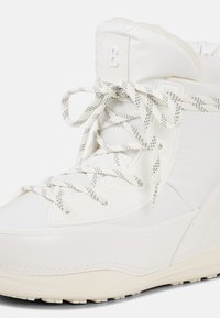Biały śniegowce z wyściełanym kołnierzem, teksturowanymi panelami oraz kontrastowymi sznurowadłami w kratkę. Trwała gumowa podeszwa zapewnia przyczepność.