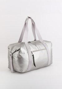 Sølvfarvet polstret duffeltaske med grå stropper, lynlåslukket hovedrum, frontlomme og struktureret overflade med en subtil glans.