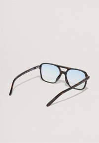 Gafas de sol carey con lentes azules, forma rectangular y un acabado brillante. Presentan un diseño robusto y patillas delgadas.