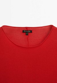 Pull rouge col rond avec une étiquette Massimo Dutti indiquant la taille moyenne et fabriqué au Vietnam.