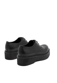 Scarpe in pelle nera con punta rotonda, suola platform nera spessa e finitura liscia. Presentano un design con lacci e un dettaglio di cucitura sottile.