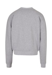 Sudadera gris de corte relajado, con cuello redondo, puños y dobladillo acanalados. Está hecha de un tejido suave, sin logotipos ni patrones visibles en la parte posterior.