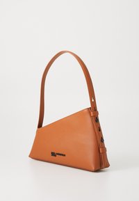 Brown leather handbag with a triangular shape, a single strap, and understated branding. Features a smooth texture and minimalist design.