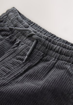 Pantalones de pana gris oscuro con una superficie texturizada, que cuentan con una cinturilla elástica y un cordón para ajustarlos.