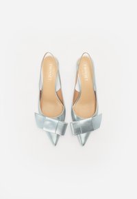 Chaussures à talons hauts argentées avec une bride arrière, à bout pointu, ornées d'un large nœud décoratif à l'avant et d'une finition lisse et brillante.