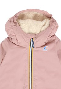 Giacca a vento per bambini di colore rosa con fodera in pile crema e zip a strisce arcobaleno sul davanti.