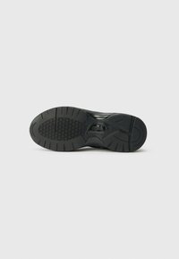 Talpă de sneaker neagră din cauciuc texturat, cu modele de fagure și caneluri pentru tracțiune. Formă rotunjită cu un toc integrat.