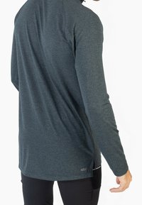 Camicia a maniche lunghe in tessuto testurizzato color verde scuro, caratterizzata da una vestibilità slim e spacchi sui lati. Etichetta con logo del brand all'orlo.