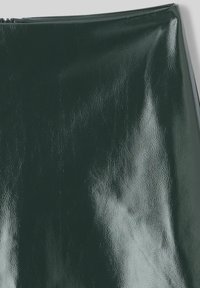 Matériau en cuir verni vert, texture lisse et finition brillante. Dispose d'une fermeture éclair sur le dessus.