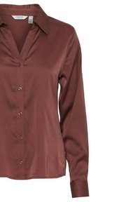 Camicia a maniche lunghe con colletto in una ricca finitura satinata marrone, con una chiusura frontale a bottoni e una superficie liscia. Presenta sei bottoni lungo la patta.