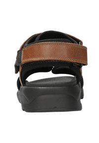 Sandales en cuir marron avec une doublure en tissu noir texturé, une semelle noire robuste et une boucle réglable pour un ajustement sécurisé.