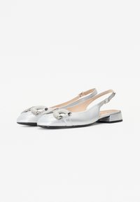 Sudraba slingback kurpes ar noapaļotu degunu, dekoratīvu siksnu ar sprādzes akcentiem un zemu bloku papēdi. Gluda ādas tekstūra.