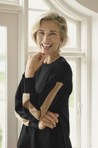 Schwarzes Sweatshirt mit langen Ärmeln, das beige Streifen an den Bündchen aufweist. Glatter Stoff, lockere Passform und klassischer Rundhalsausschnitt.