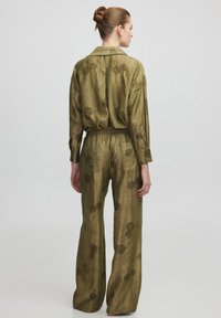 Ensemble en tissu léger vert olive comprenant une chemise ample à manches longues et un pantalon à taille élastique, orné de motifs floraux.