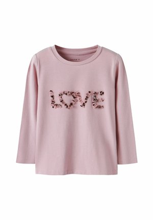 Chemise à manches longues rose clair avec des lettres en tissu volantées épelant "LOVE" sur la poitrine et un col rond.