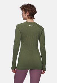 Langärmliges Shirt in olivgrün, aus glattem Stoff gefertigt. Hat ein tailliertes Design mit Rundhalsausschnitt und einem kleinen Logo auf der Rückseite.