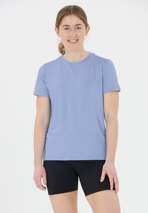 Lichtblauw sportt-shirt van ademend materiaal, met korte mouwen en een ronde hals. Gecombineerd met zwarte shorts voor een sportieve uitstraling.