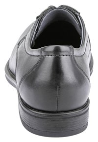 Scarpa in pelle nera con finitura liscia, tacco arrotondato e dettagli cuciti. La suola è piatta con un pattern di grip testurizzato.