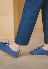 Blå mockaskor med platt sula, med snörning och en bakre dragflik, matchade med mörk denimcropped byxor.