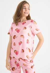 Rosa pyjamaset bestående av en kortärmad topp och matchande byxor, prydda med lekfulla motiv av igelkottar och hjärtan.