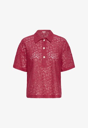 Koszulka polo z krótkim rękawem i kołnierzykiem, wykonana z teksturowanej koronkowej tkaniny w malinowym kolorze z okrągłymi wzorami, z zapięciem na guziki i trzema białymi guzikami.