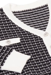 Fekete-fehér textúrált kötött kardigán fényes szálakkal, V-nyakkivágással, díszes strasszkövekkel díszítve.