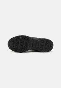 Schwarze Sport-Schuhsohle, strukturiertes Gummimaterial, mit tiefen Rillen und Mustern für Traktion, mit markenspezifischen Details an der Seite.