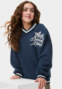 Sweatshirt marine avec le texte blanc "Anti Social Mood" et un col côtelé. Comprend des épaules tombantes et des poignets rayés. Tissu doux et texturé.