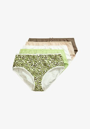 Donna che sistema la biancheria intima a vita alta con stampa leopardata, indossa un reggiseno coordinato, in piedi contro una parete bianca con capelli sciolti.