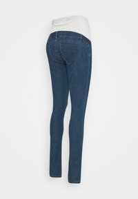 Mörkblå denim skinny jeans med en ljusgrå elastisk midjeband, som har en medelhög midja och standard bakfickor. Slät textur.