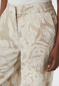Beige gestreepte broek met een zachte textuur, met een hoge taille en plooien, die een abstract bladontwerp in lichte en donkere tinten toont.
