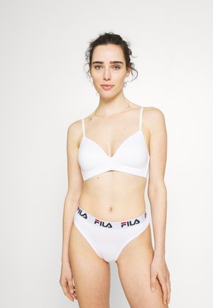 White bralette with adjustable straps and a plunging neckline, paired with white thong featuring a black and red FILA logo waistband.