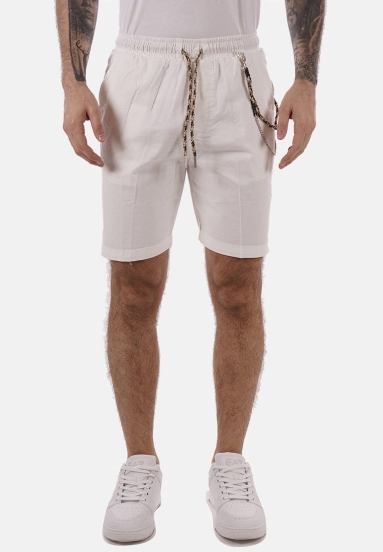 Pantalones cortos blancos con una cintura elástica, cordón ajustable en un patrón mixto y dobladillos enrollados. Llevados con zapatillas blancas, mostrando un look casual.