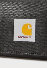 Portafoglio nero con superficie testurizzata, caratterizzato da un logo rettangolare giallo e bianco con "carhartt" in bordeaux sottostante.