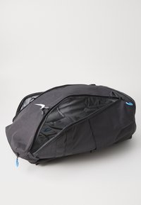 Sac de voyage noir avec une surface texturée, disposant d'un grand compartiment principal, de fermetures éclairs et d'une languette de traction bleue.