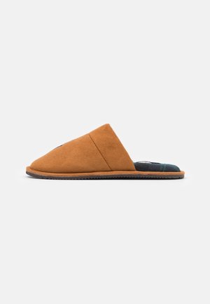 Chausson marron en daim à enfiler avec une doublure intérieure à carreaux noire et verte et une semelle plate texturée vu de profil.