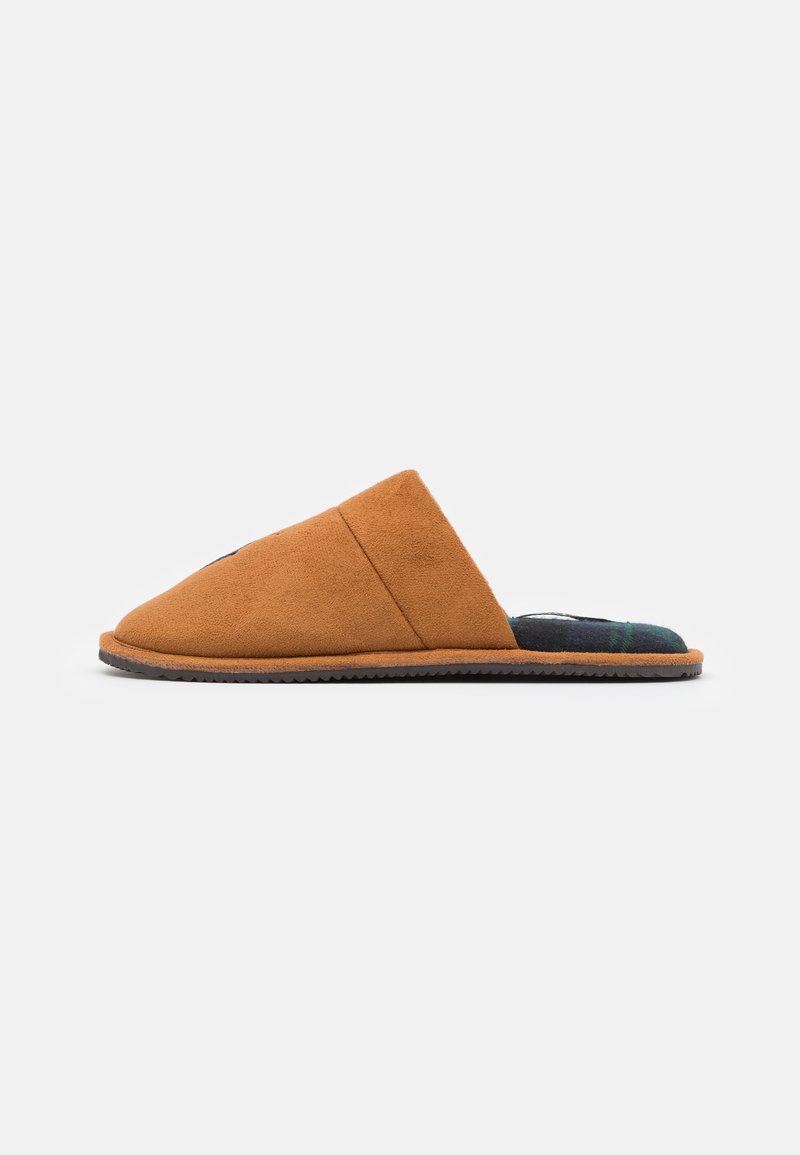 Chausson marron en daim à enfiler avec une doublure intérieure à carreaux noire et verte et une semelle plate texturée vu de profil.