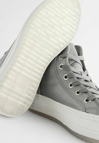 Gray high-top sneakers with smooth leather upper, metal eyelets, and light gray laces. The thick, textured rubber sole is white with clear accents.