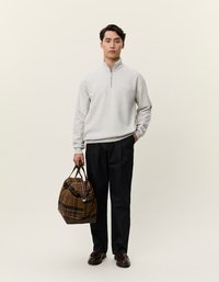 Gaiši pelēka ievelkama džemperis ar rāvējslēdzēju, tumši bikses un brūns šķērsota soma ar tumšiem akcentiem un ādas rokturi. Vienkāršs fons.