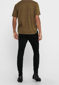 Brun texturerad kortärmad skjorta, kombinerad med svarta slim-fit byxor och svarta ankelstövlar. Enkelt design, neutrala färger och figursydd form.