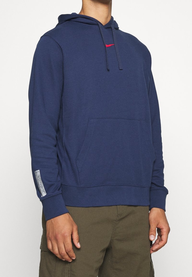 Navy blue pullover hoodie made of soft fabric, featuring a kangaroo pocket and red logo accent. Includes ribbed cuffs and hem.