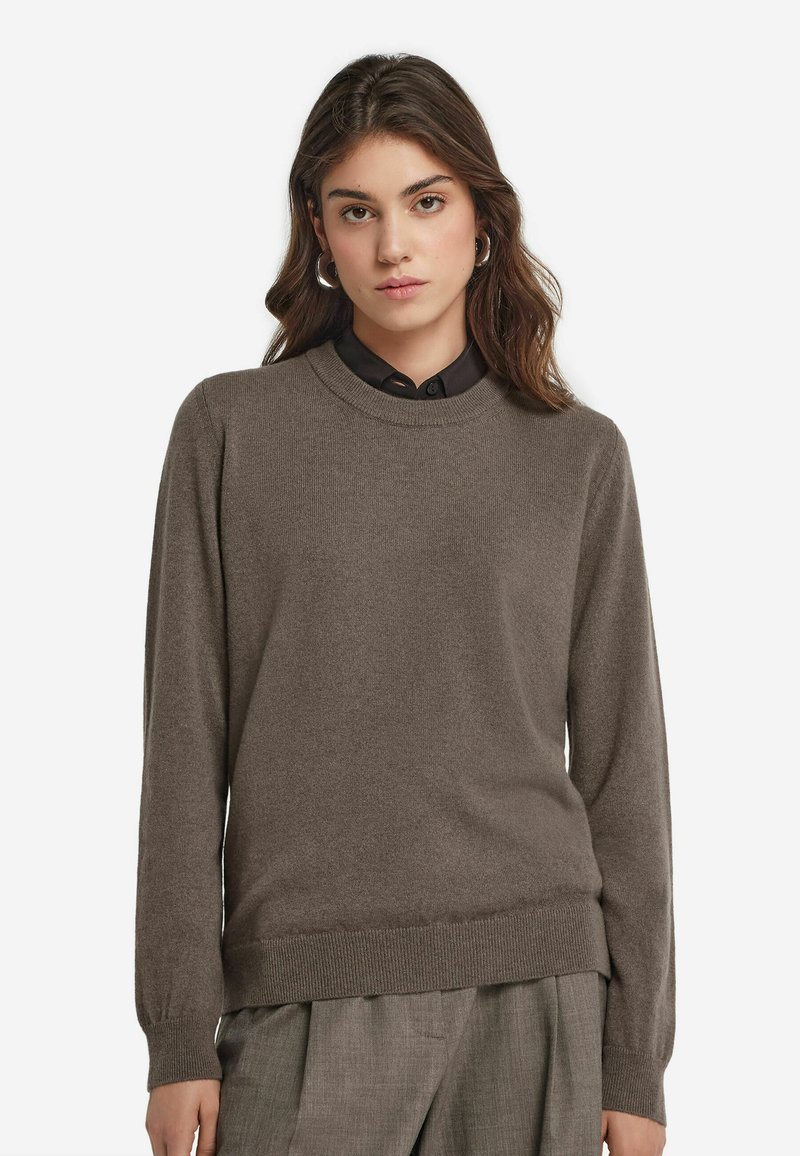 Brunstickad tröja med rund halsringning och ribbade ärmslut, kombinerad med en svart skjorta med krage. Mjuk textur, avslappnad passform och enhetlig färg.