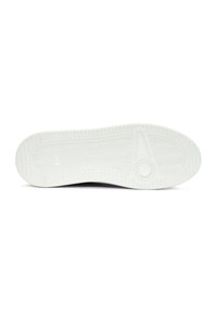 Suela de zapatilla de goma blanca con patrón de espiga, punta redondeada y emblema circular. Textura suave con surcos de tracción prominentes.