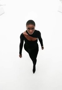 Zwarte lange mouw fitted bodysuit met een asymmetrische uitsnijding op de borst, gedragen door een persoon tegen een witte achtergrond.