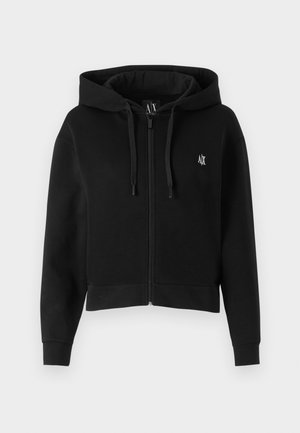 Haut à capuche court noir en tissu doux, doté d'une fermeture éclair à l'avant, d'une capuche avec cordon de serrage et d'un petit logo brodé sur la poitrine gauche.