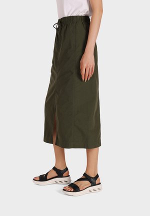 Gonna di cotone verde oliva a lunghezza ginocchio con vita elastica e cordoncino. Presenta uno spacco frontale ed è abbinata a sandali neri.