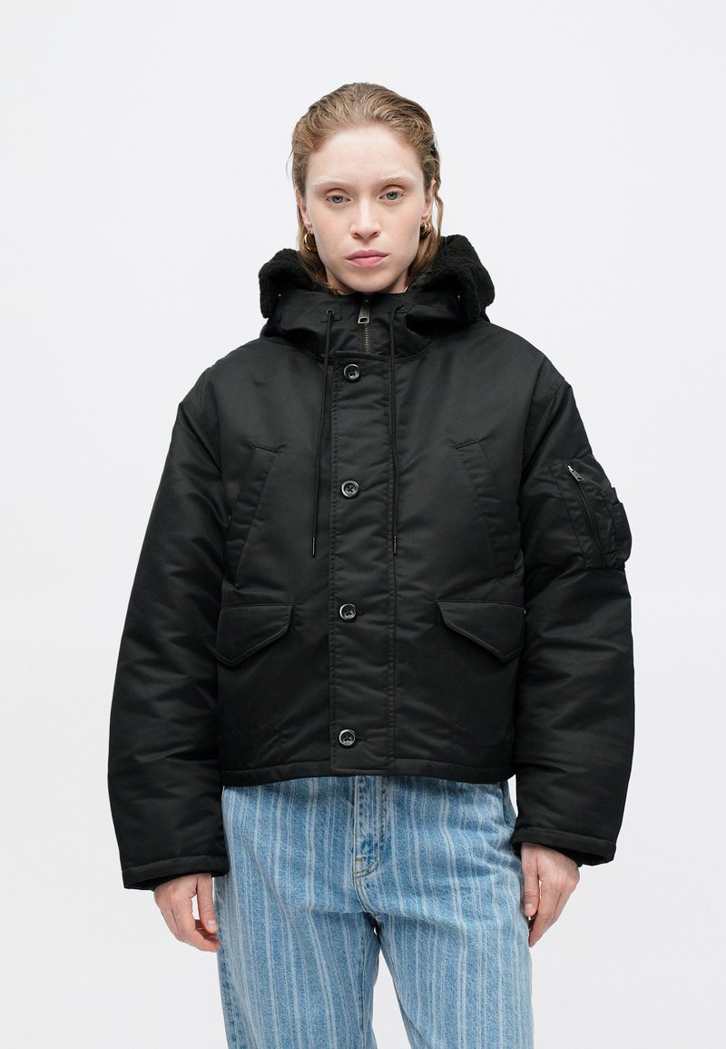 Schwarze gepolsterte Jacke mit Kapuze, Knöpfen auf der Vorderseite und zwei großen Fronttaschen, einer strukturierten Innenseite und einer Reißverschlusstasche am Arm.