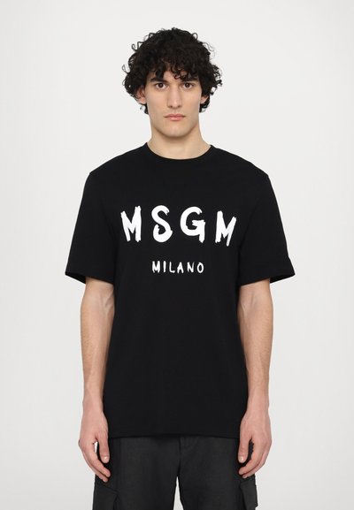 Fekete pamut póló merész fehér "MSGM" és "MILANO" felirattal. Klasszikus kerek nyakkivágás, rövid ujjakkal, laza szabású.