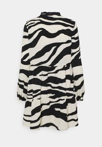 Robe à manches longues rayée zébrée noire et blanche, avec une taille froncée et une jupe évasée, vue de dos.